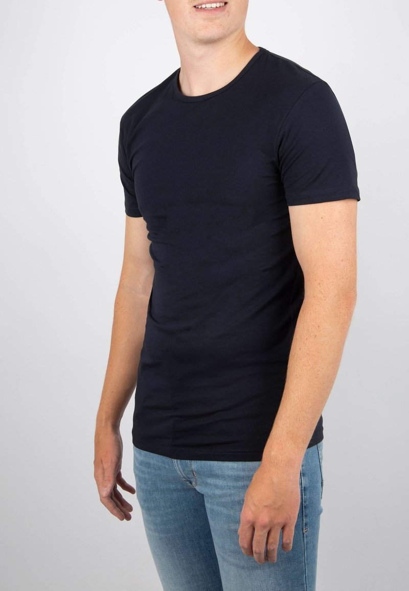 Navyblauwe t-shirt gemaakt van zachte katoen, met een ronde hals, korte mouwen en een slim-fit ontwerp. G gedragen met lichtblauwe jeans.