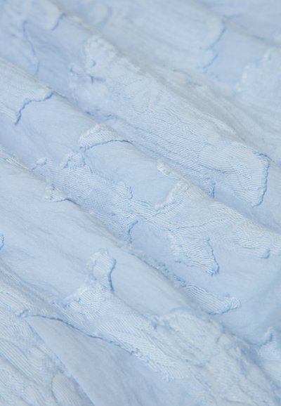 Tessuto azzurro chiaro con ricamo testurizzato, caratterizzato da una superficie morbida e leggermente stropicciata. Il motivo include forme astratte sottili.