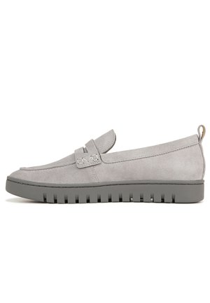 Mocassins en daim gris avec une semelle en caoutchouc plate, ornés d'une bride décorative et de détails de couture. Le design est élégant et minimaliste.