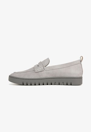 Mocassins en daim gris avec une semelle en caoutchouc plate, ornés d'une bride décorative et de détails de couture. Le design est élégant et minimaliste.