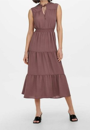 Robe midi mauve sans manches avec jupe à volants, taille cintrée, encolure en trou de serrure avec lien, portée avec des mules à talons ouvertes noires.