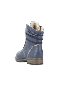 Botte cheville en cuir marine avec une finition texturée, bout rond, doublure en peluche, coutures décoratives et un talon en bois empilé.