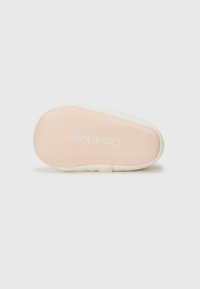 Semelle de sneaker blanche avec une semelle intérieure couleur pêche. Présente une texture lisse et le logo "Calvin Klein" imprimé en blanc sur le dessous.