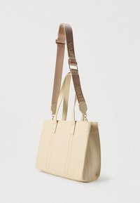 Bež usnjena torba z dvema ročajema, širokim ramenim trakom z napisom "VALEN" in navpičnim šivom za okras.