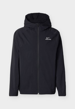 Must Nike Pro kapuutsiga jakk esikaanega ja fliisvoodriga, nähtud tavalise tausta peal.