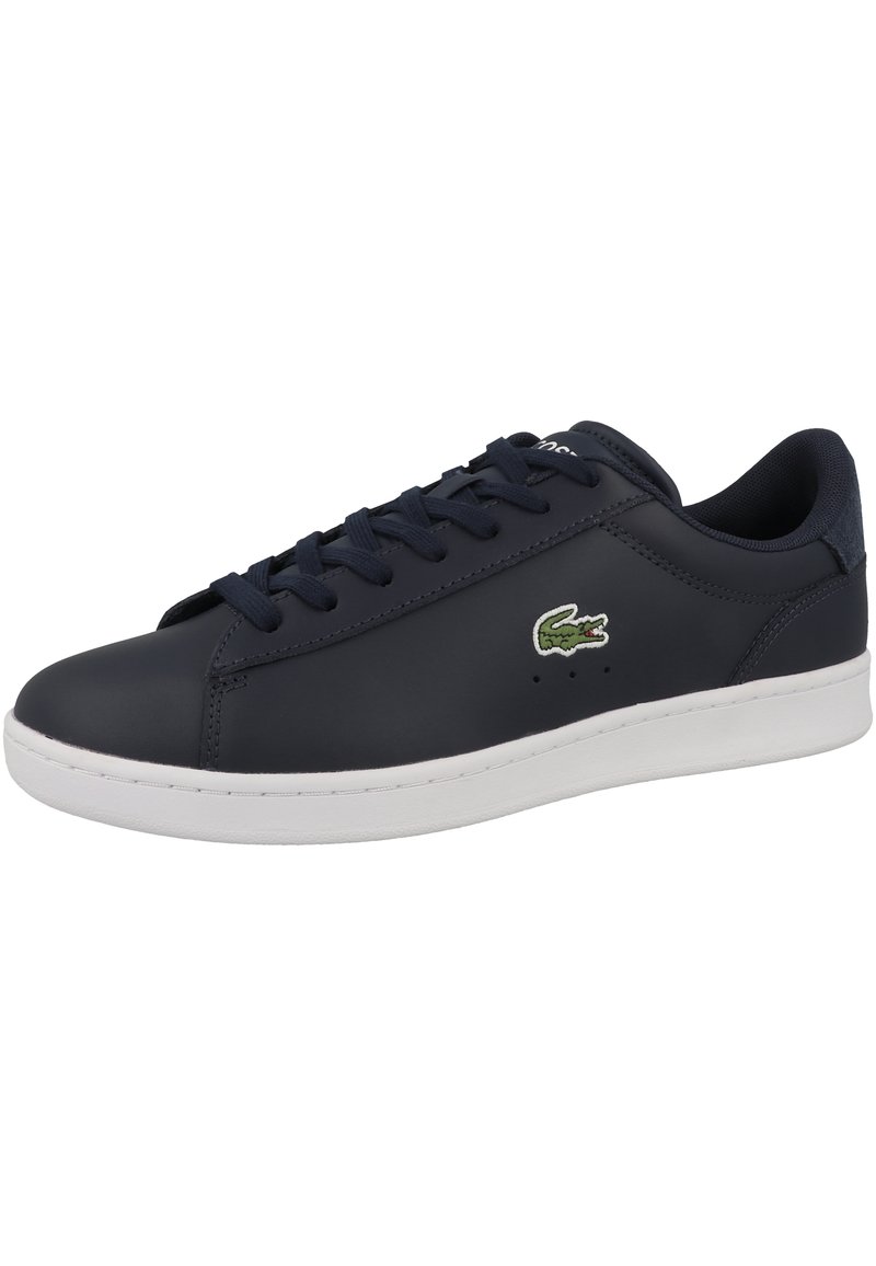 Baskets en cuir bleu marine avec semelle en caoutchouc blanche, présentant un bout arrondi, un laçage et un logo crocodile vert Lacoste sur le côté extérieur.