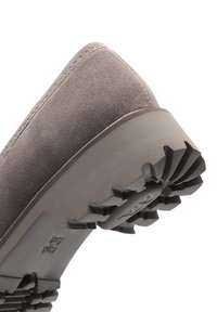Close-up of taupe suede shoe with pointed toe and thick rubber sole featuring deep tread for traction.
