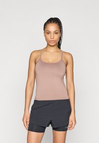 Débardeur marron à fines bretelles, texture lisse, associé à un short noir avec un design à couches superposées et des poches. Style simple et ajusté.