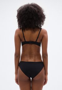 Set de sutien și bikini negri cu bretele reglabile și un design clasic. Textură netedă, detalii minime și închidere simplă cu clemă.