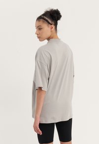 Relaxed-fit, short-sleeve t-shirt in light gray cotton. Features a simple crew neckline and falls below the hips. Worn with black shorts.