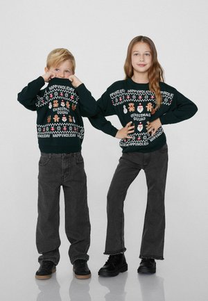 Green knitted Christmas sweaters with festive patterns, features snowmen, Santa, and gingerbread. Paired with dark gray pants and black shoes.