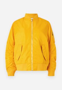 Giacca bomber gialla con zip frontale, colletto e polsini a coste, due tasche laterali e una tasca con zip sulla manica. Tessuto liscio e lucido.