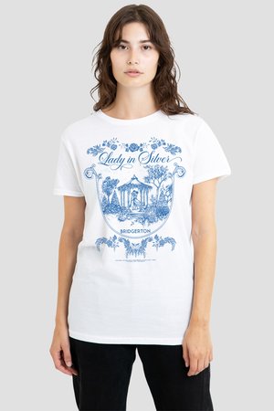 Junge Frau trägt weißes T-Shirt mit blauem Blumen- und Pavillon-Design sowie dem Text „Lady in Silver“ und „Bridgerton“ auf der Vorderseite.
