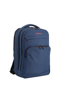 Zaino blu navy realizzato in tessuto, dotato di più scomparti, cerniere e un logo. Texture liscia con accenti neri a contrasto.