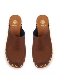 Sabots en cuir marron avec une finition texturée, ouverture à l'arrière, accents en métal doré autour de la semelle, et une base en bois lisse.