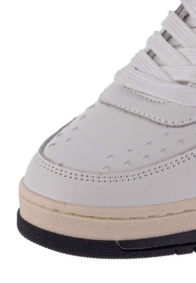 Sneaker bianco in pelle con dettagli perforati, lacci piatti e suola intermedia color beige chiaro. Presenta una suola nera testurizzata.