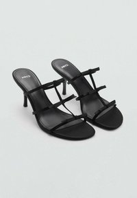 Musta korolliset sandaalit, joissa on ohut naru ja neliön muotoinen kärki. Valmistettu sileästä materiaalista, jossa on kapea stiletto-korko ja minimalistinen muotoilu.