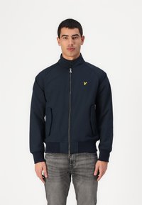 Giacca zip-up blu marina con colletto alto, due tasche laterali e un piccolo logo giallo sul petto. Tessuto liscio e design attillato.