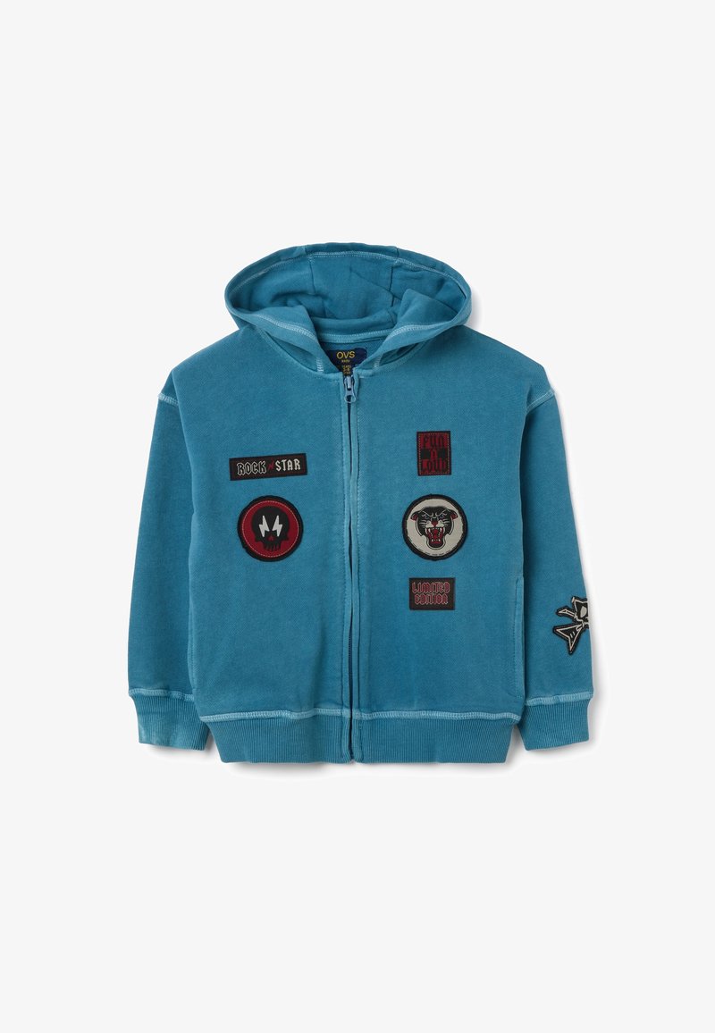 Felpa con zip color teal e due tasche frontali. Presenta vari patch ricamati, tra cui "ROCK STAR" e un design di teschio. Tessuto morbido.
