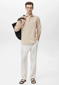 Light beige button-up shirt, white striped pants, black sandals, gray tote bag. Shirt features a pocket; pants have vertical stripes.