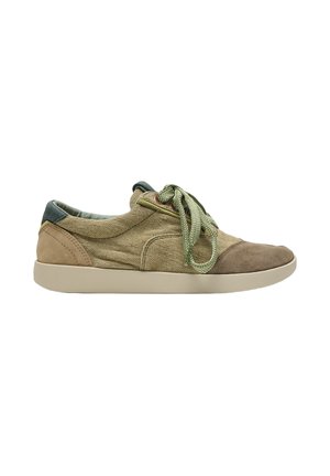 Zapatilla casual de perfil bajo con parte superior de tela y ante beige, cordones verdes y suela de goma beige clara, vista desde un lateral sobre fondo blanco.