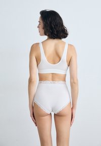 White lingerie set consisting of a bralette and high-waisted panties. Features delicate lace accents and a smooth fabric texture.