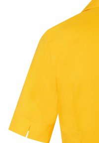 Geel overhemd met korte mouwen en een kraag. Soepele textuur en strakke lijnen, voorzien van een zijsplit bij de mouw voor extra detail.
