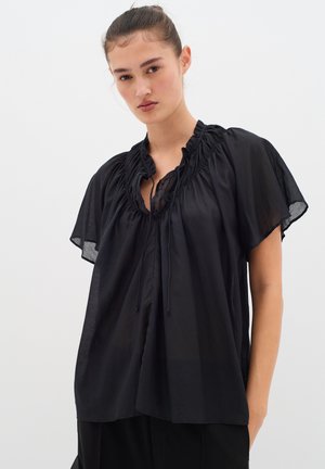 Schwarze, leichte Bluse mit gerafftem Ausschnitt, kurzen, schwingenden Ärmeln und Bindebanddetails. Durchsichtiger Stoff und lockere Passform.