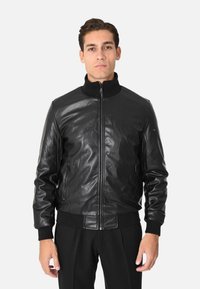 Giacca bomber in pelle nera con chiusura a zip, colletto, polsini e fondo a costine. Design semplice con due tasche laterali e texture liscia.