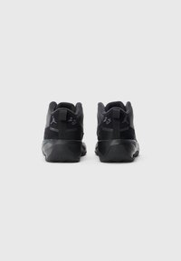 Et par svarte høye sneakers med "23" og Jumpman-logo på hælen, fotografert bakfra mot en enkel hvit bakgrunn.