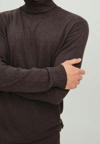 Pull col roulé marron en tissu tricoté doux et texturé. Coupe ajustée avec manches longues, doté d'un col et de poignets côtelés.