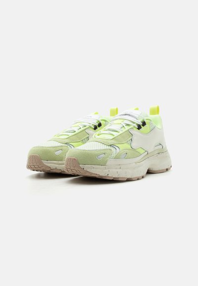Ζευγάρι ανοιχτοπράσινα και λευκά chunky sneakers με λεπτομέρειες από δίχτυ και σουέτ, χοντρή σπογγώδης σόλα με στίγματα και κίτρινες θηλιές σε λευκό φόντο.