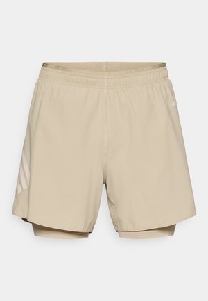Beige atletikshorts i letvægtsstof med snøre i taljen og kontrasterende meshforing. Har tre stribede accenter på siden.