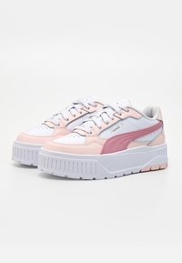 Paar weiße und rosa Puma Plateau-Sneaker mit Schnürung vorne und dicken, profilierten Sohlen auf einfarbigem Hintergrund.