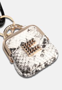 Pochette en fausse peau de serpent blanche et noire avec des accessoires dorés, présentant un design hexagonal clouté à l'avant et une attache porte-clés.