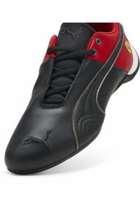 Černé kožené tenisky s červenými a bílými akcenty, s šněrováním, texturovaným černým síťovaným jazykem a logem Puma.