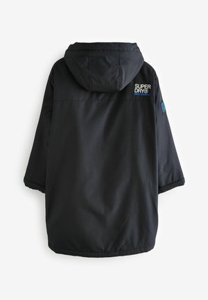 Black waterproof jacket with hood, featuring a textured fabric, a loose fit, and a logo on the back. Durable design, suitable for outdoor use.