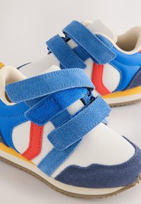 Baskets pour enfants avec bandes velcro bleues, mesh blanc, accents latéraux rouges et bleus, et intérieur beige rembourré.