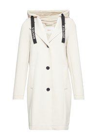 Cappotto lungo color crema con cappuccio, caratterizzato da cinghie nere con la scritta "S.OLIVER", chiusura con bottoni, due tasche laterali e un fit sartoriale.