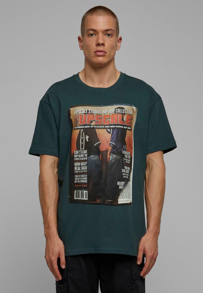 Grøn bomulds t-shirt med et stort grafisk tryk af et magasinomslag; har oversized pasform og korte ærmer.