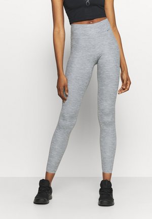 Leggings gris en matériau texturé et extensible avec une taille haute. Portés avec un haut noir court et des chaussures de sport noires.