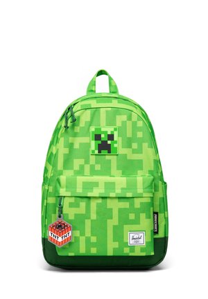 Sac à dos pixélisé vert avec patch visage de Creeper Minecraft et porte-clés TNT, poche avant et étiquette de la marque Herschel en bas.