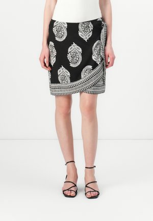 Jupe noire enroulée avec un motif paisley blanc et des finitions métalliques. Fabriquée en tissu léger, elle présente une silhouette élégante et des détails soignés.