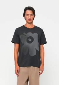 T-shirt in cotone nero con un grande motivo floreale grigio. Le maniche corte e il collo tondo completano la vestibilità rilassata.