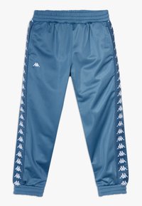 Pantaloni sportivi blu in materiale liscio con vita elasticizzata, caratterizzati da dettagli bianchi con il logo lungo le cuciture laterali.