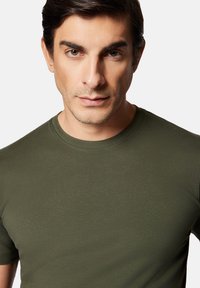 Oliwkowy t-shirt z okrągłym dekoltem, wykonany z gładkiej bawełny, z krótkimi rękawami, dopasowany krój i minimalne detale szwów.