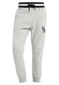 Světle šedé tepláky vyrobené z měkké látky, se stahovacími šňůrkami, elastickým pasem s černobílými pruhy a výrazným akcentem písmene "N".