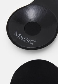Black shoe insole with a circular cutout, featuring a smooth surface and textured edges, branded with "MAGIC® BODYFASHION" in silver.