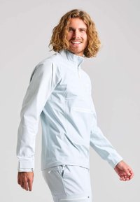 Hellblaue Zip-Jacke mit hohem Kragen, langen Ärmeln und seitlichen Reißverschlusstaschen. Hergestellt aus glattem, leichtem Material mit einem schlichten Design.