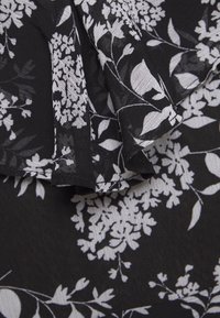 Black fabric featuring white floral design with intricate patterns and textures, displaying a soft, lightweight, and slightly sheer material.